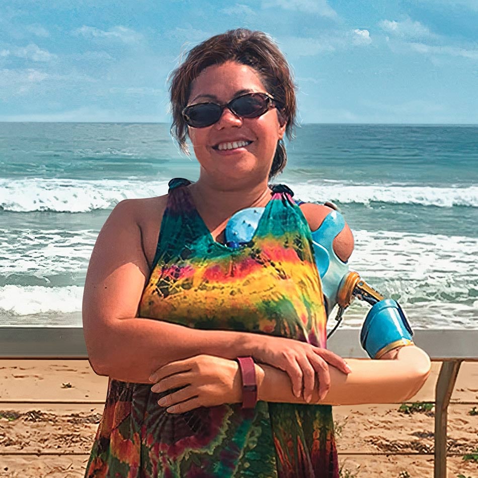Claudia Mitchell wearing sunglasses with the beach and ocean behind her