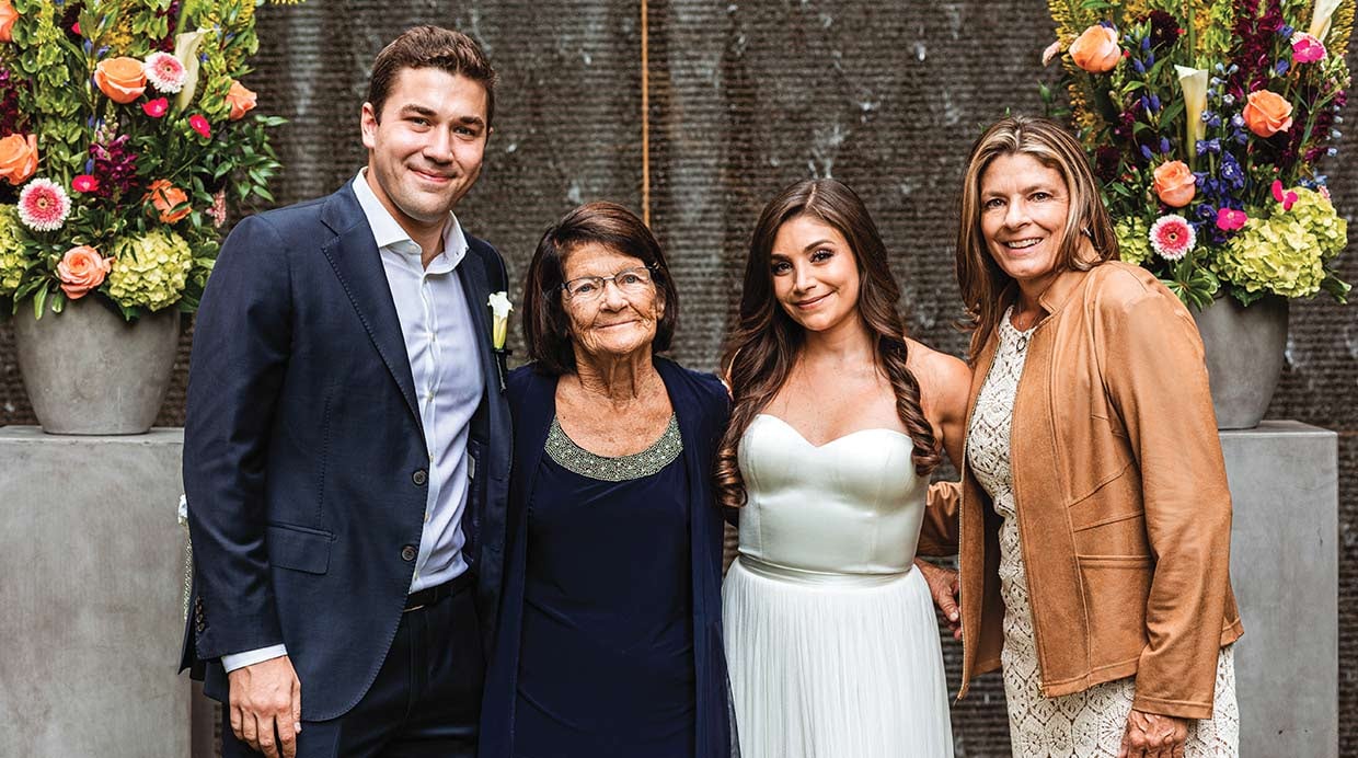 one man and three woman, standing for a photo. The second woman from the right is a bride.