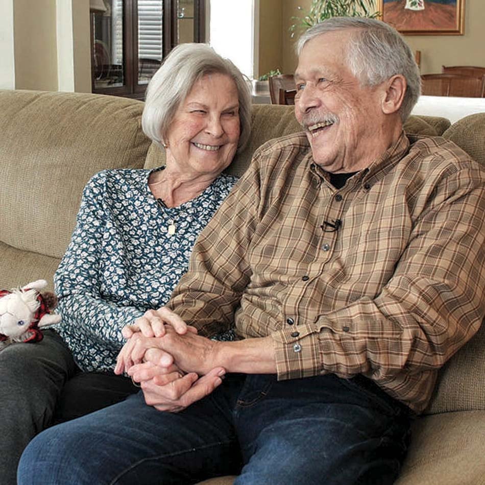 Dorinda and Jerry sitting on a couch with their white dog