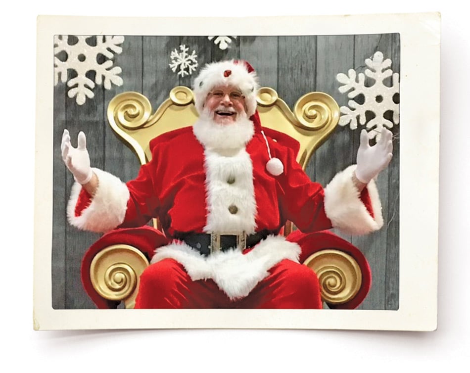 polaroid photograph of santa sitting on a gold chair with his arms up and smiling 