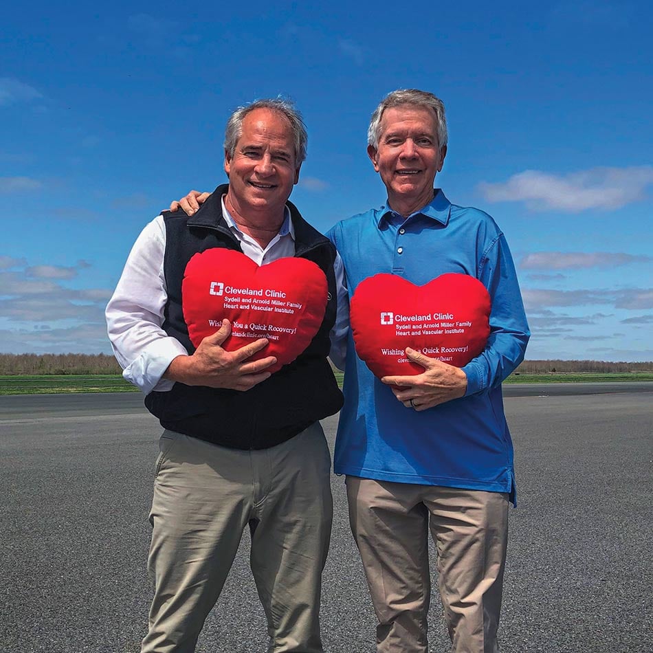 Steve Golding, right, and Mark Nicholas holding red plush hearts, which a blue sky behind them