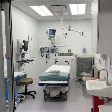 Emergency room exam room bed sink chairs rolling stool monitors wall cabinet computer rolling drawer cabinet