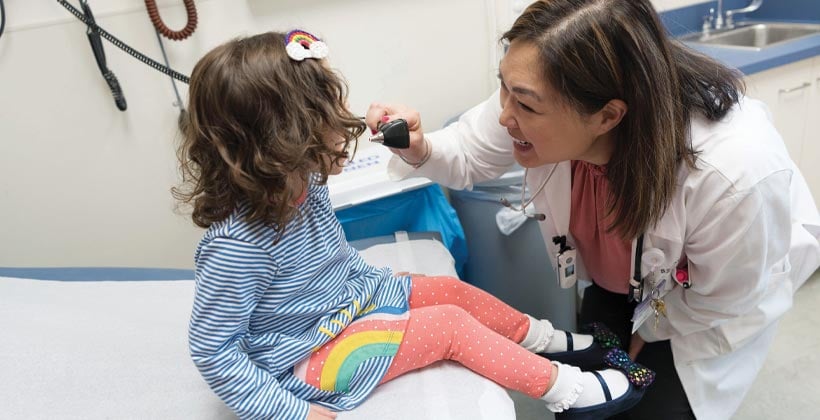 Asian female doctor smiling at young female patient in exam room