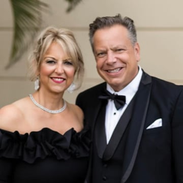 Smiling middle aged couple blond woman wearing black cocktail dress man wearing black tuxedo