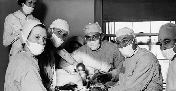 group of surgeons around a patient in mid-surgery