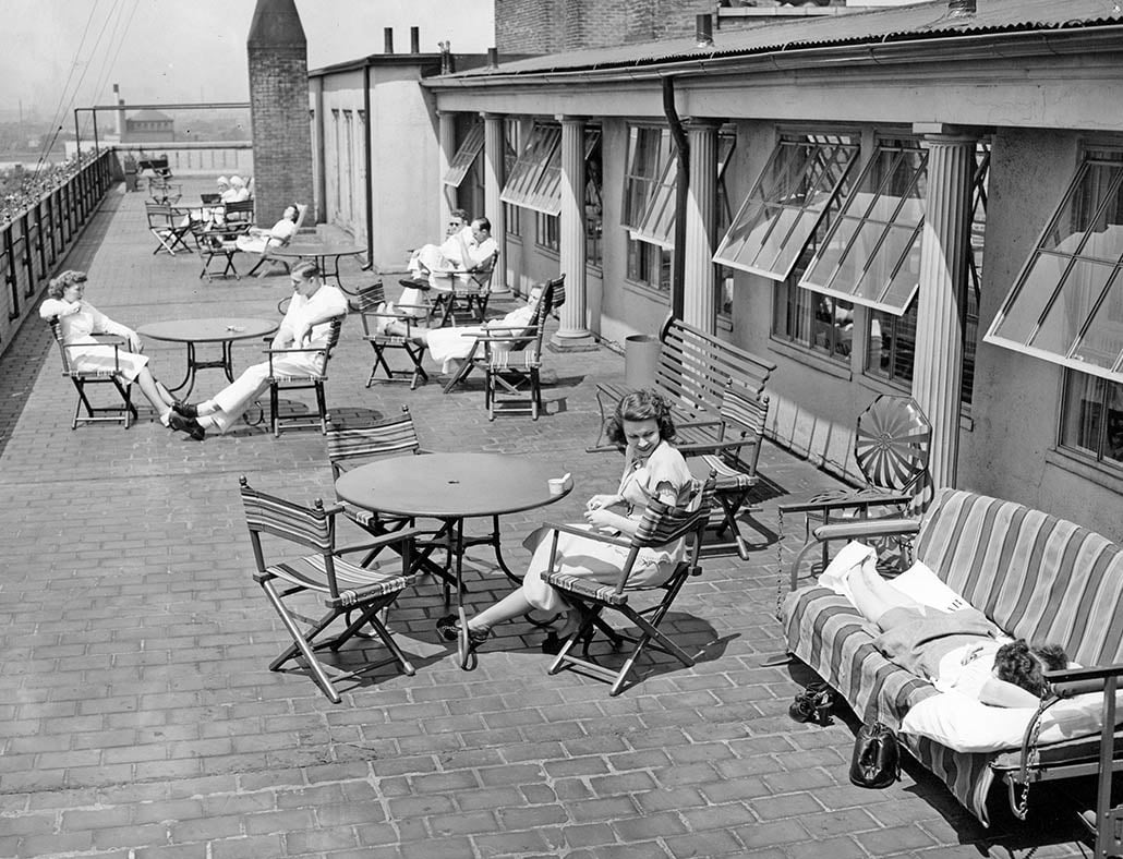 black and white photo of men and women sitting on a rooftop patio