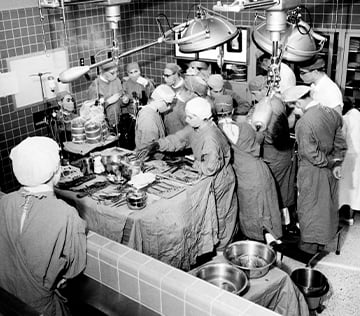 black and white image of multiple doctors in a surgery wearing surgical scrubs