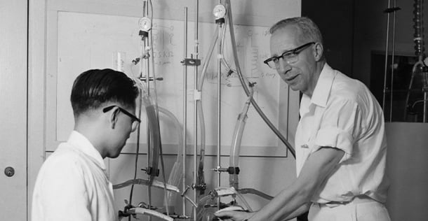 black and white image of an older man and a younger man looking at medical equipment