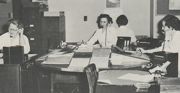 Image of 4 woman with telephones to their ears, sitting at desks