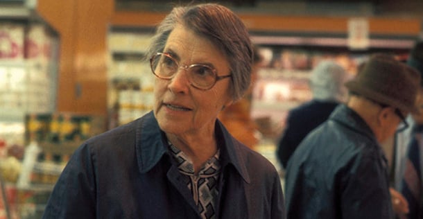 Helen Brown, PhD standing in a grocery store, holding two packages of red meat, looking out of frame