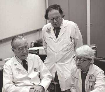 Drs. Page, Gifford and Dustan looking at paperwork on a table