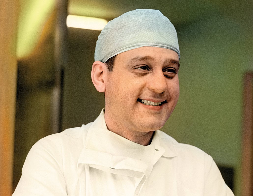 Dr. Rene smiling, looking out of frame, wearing a medical cap and uniform