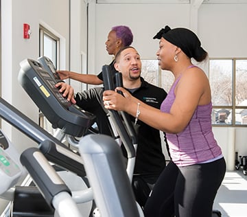 a male trainer working with a woman on a treadmill
