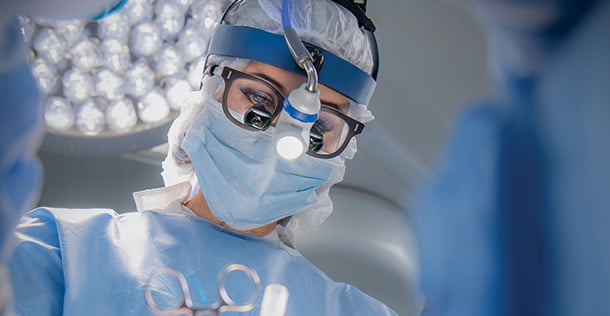 female doctors wearing medical gear, glasses and a light on her head