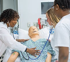 Student nurses practicing on a dummy patient
