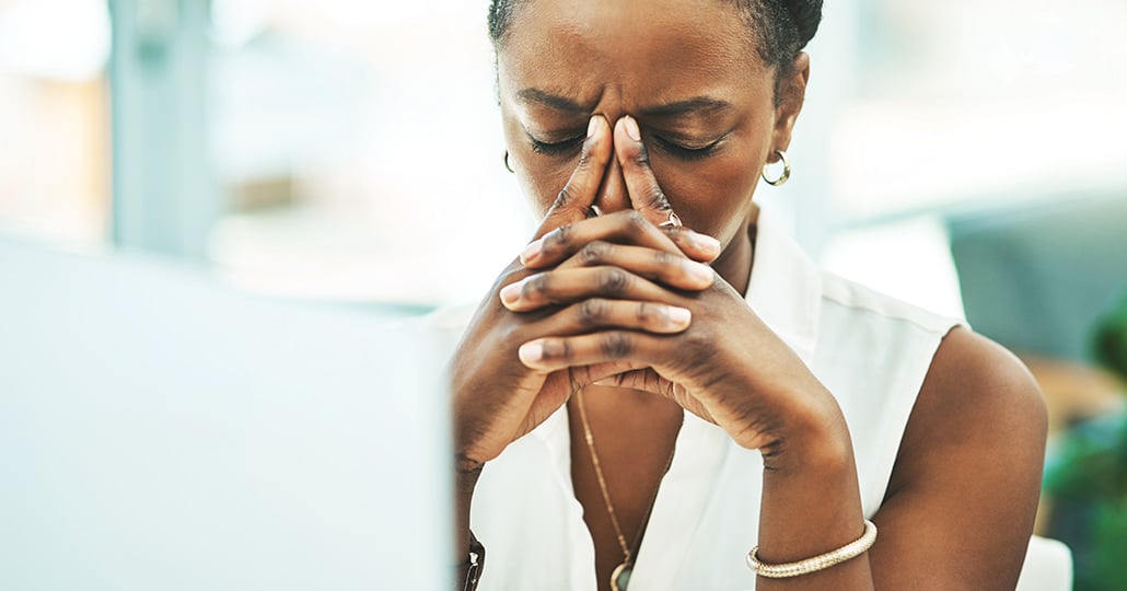 Woman pressing her index fingers into the space between her eyes, with her eyes closed.