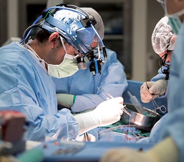 Doctor in blue surgical gear, wearing medical head gear to operate on patient