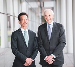 Larry Pollock and Stewart Kohl standing outside in a corridor, wearing suits for a photo