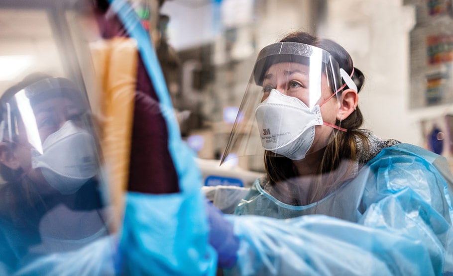 A female doctor wearing medical protective gear, helping a patient.