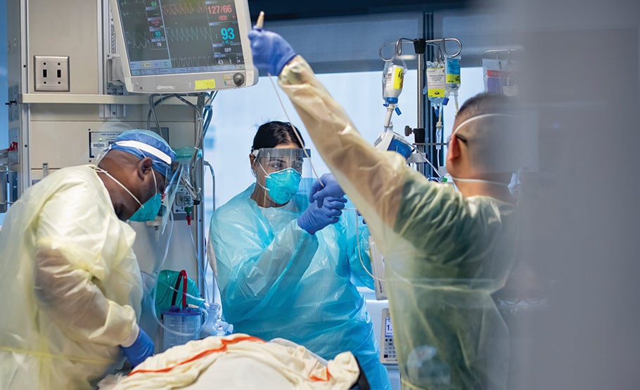 Three doctors in the ICU working with a patient