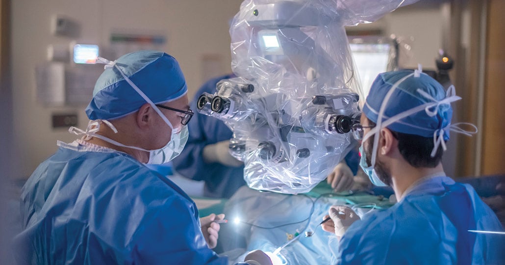 Two doctors wearing medical gear working with a machine for a procedure