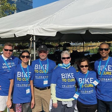 six people wearing velosano tshirt and sunglasses posing for a picture