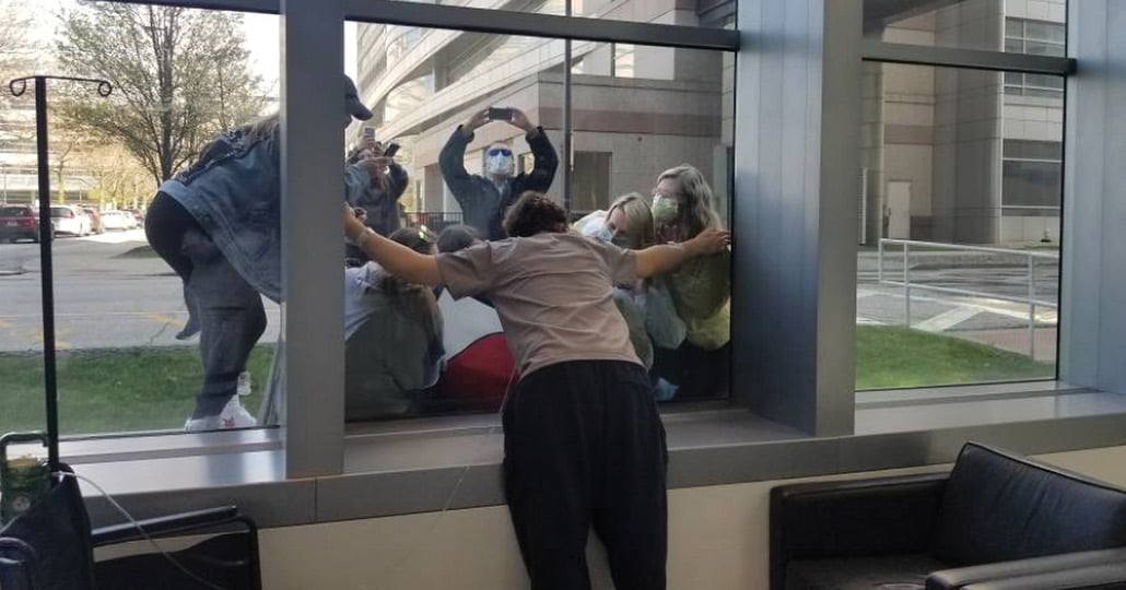 Person leaning against glass with arms out 
