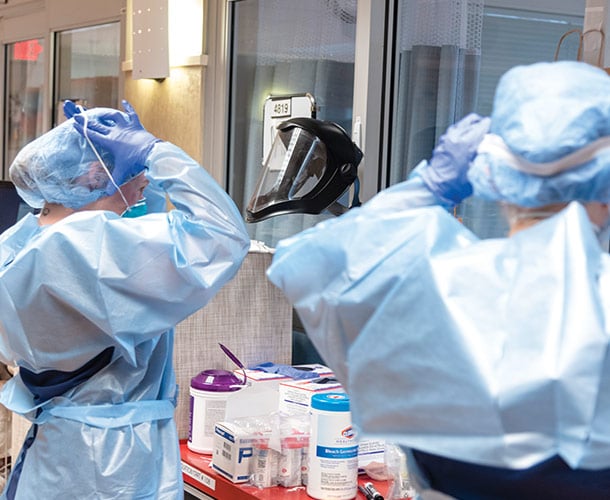two people putting on protective gear in a hospital