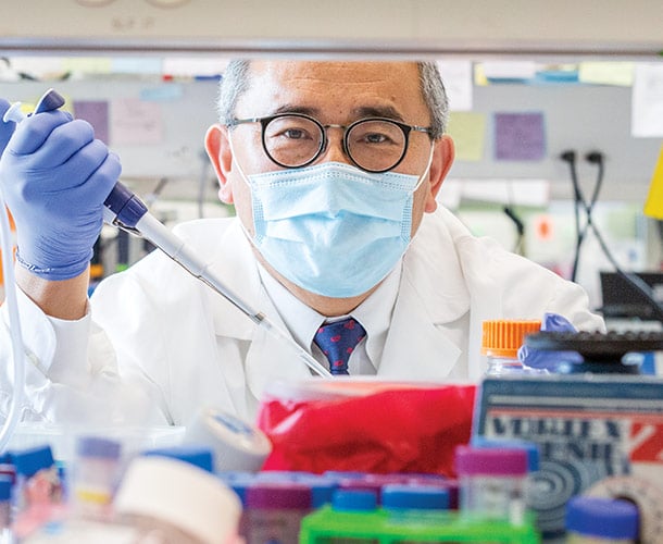 Jae Jung PhD wearing a face mask holding up a tool