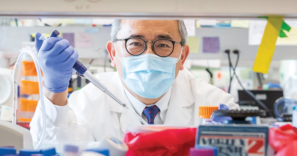 Doctor wearing glasses and a face mask holding a testing tool, shown between shelves holding medical supplies.