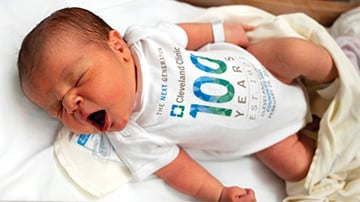 An infant wearing a white onesie that says 