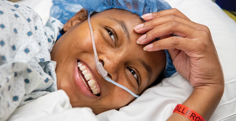 Black woman in hospital gown and cap with oxygen tube