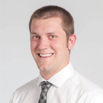 Portrait headshot of a man wearing a white shirt and plaid gray tie