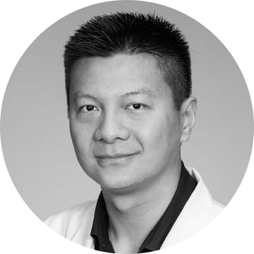 Black and white portrait headshot of Asian man in a dark shirt with a white lab coat