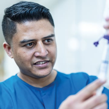 Male nurse in blue scrubs fills syringe