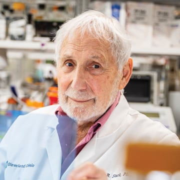 Senior man in lab wearing white lab coat over pink button down shirt