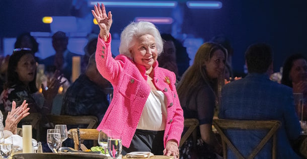 Senior woman in pink jacket waving