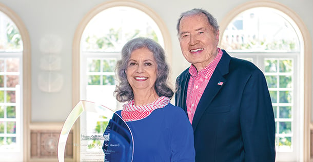 Senior couple standing next to award