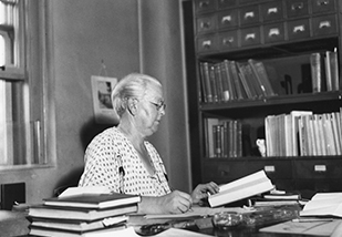 Amy Rowland at desk reading a book