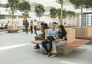 A man and woman sitting on a bench inside the Health Education Campus